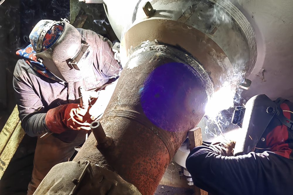 Soldadores de Grupo Galicia ejecutando soldadura en tubería de gran diámetro, con el arco eléctrico iluminando la junta